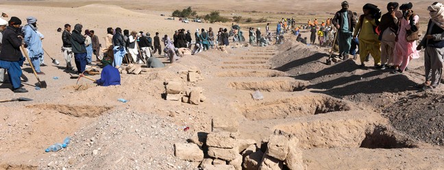 Afegãos cavam sepulturas para os corpos das vítimas dos terremotos na vila de Sarbuland, distrito de Zendeh Jan, na província de Herat, em 8 de outubro de 2023 — Foto: Mohsen KARIMI / AFP