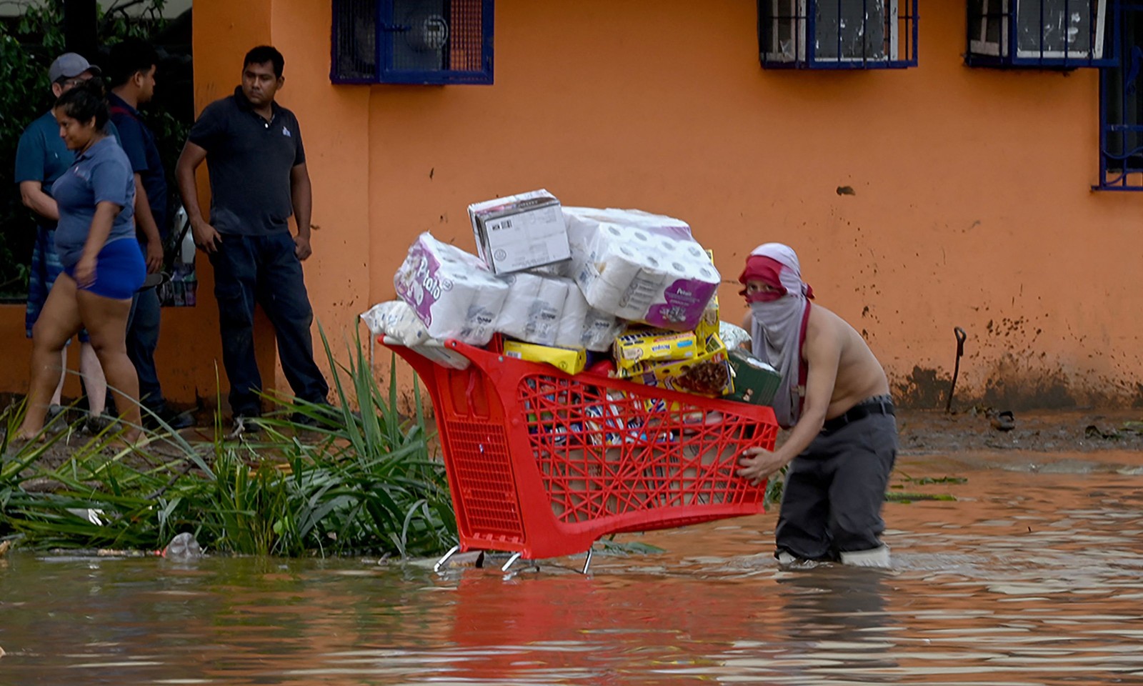 Um saqueador carrega um carrinho de compras cheio de mercadorias roubadas de um supermercado após a passagem do furacão Otis em Acapulco, estado de Guerrero, México — Foto: FRANCISCO ROBLES/AFP