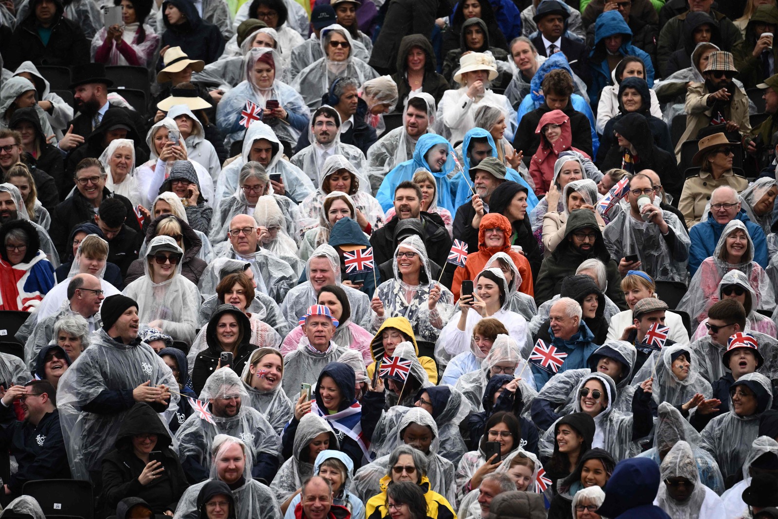 Público aguarda para assistir à passagem do rei Charles III e da rainha no Diamond State Coach, no centro de Londres — Foto: Marco BERTORELLO / AFP