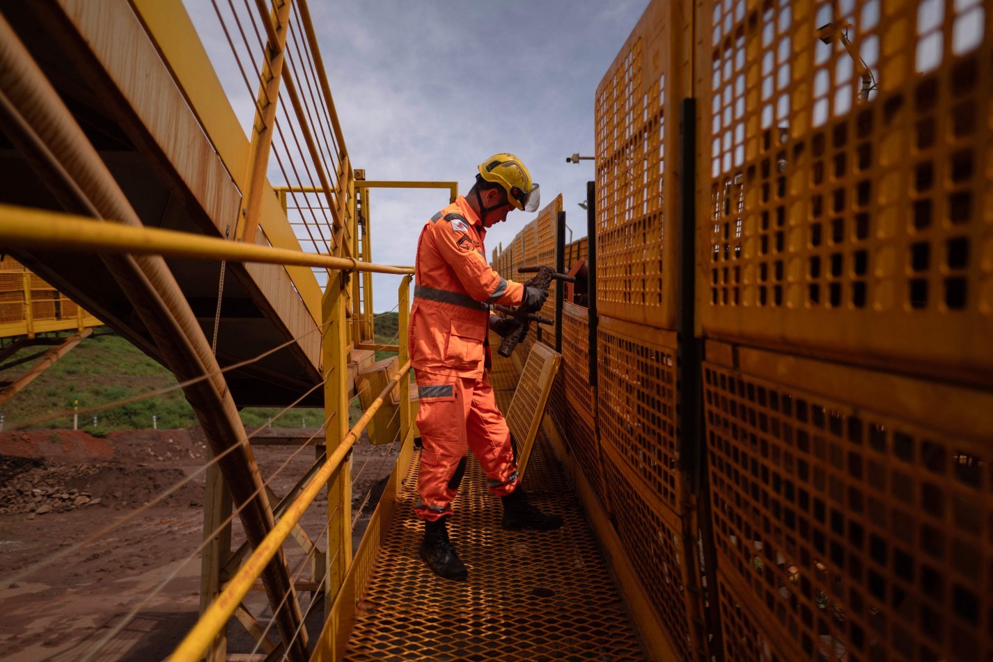 Bombeiro recolhe objeto encontrado entre rejeitos de minério em um dos postos de busca onde ficava o terminal ferroviário de cargas da mina, em Brumadinho — Foto: Douglas Magno / AFP