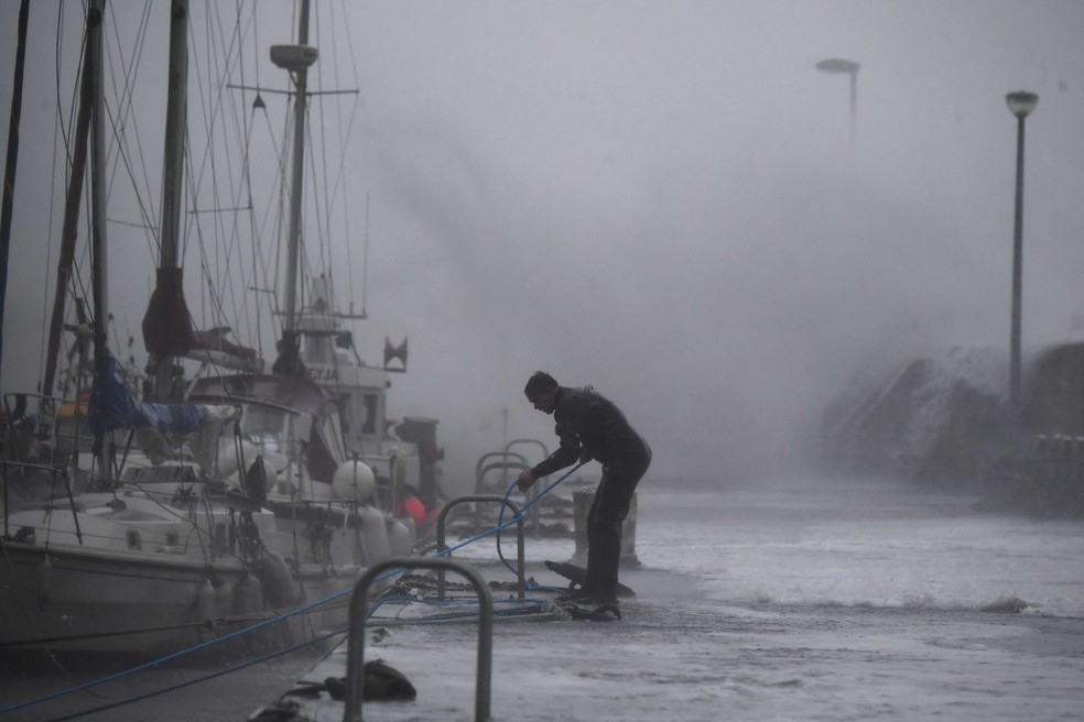 O proprietário de um barco enfrenta as condições dentro do porto para proteger os barcos em Stonehaven, na costa leste da Escócia — Foto: ANDY BUCHANAN/AFP