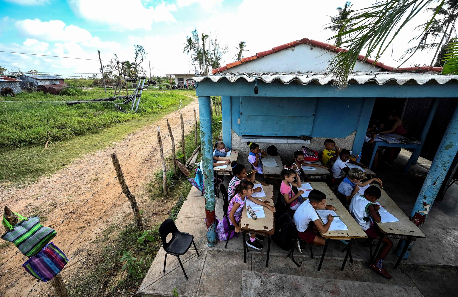 Alunos assistem a uma aula na porta de uma casa em La Coloma, província de Pinar del Rio, Cuba. — Foto: YAMIL LAGE / AFP