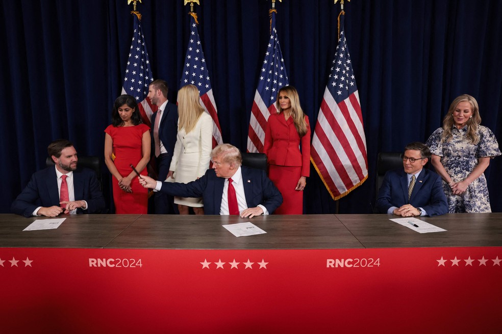 Candidato à Presidência dos EUA, Donald Trump (C), empresta caneta ao candidato a vice, J.D. Trump, em cerimiônia de assinatura de documentos de candidatura — Foto: Win McNamee/Getty Images/AFP