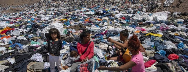 Mulheres 'garimpam' roupas em meio a toneladas descartadas no deserto do Atcama, no Chile Foto: MARTIN BERNETTI / AFP Vista aérea das toneladas de roupas descartadas nas colinas do deserto do Atacamo, na região de Alto Hospício Foto: MARTIN BERNETTI / AFP Vista aérea das toneladas de roupas descartadas nas colinas do deserto do Atacamo, na região de Alto Hospício  — Foto: MARTIN BERNETTI / AFP