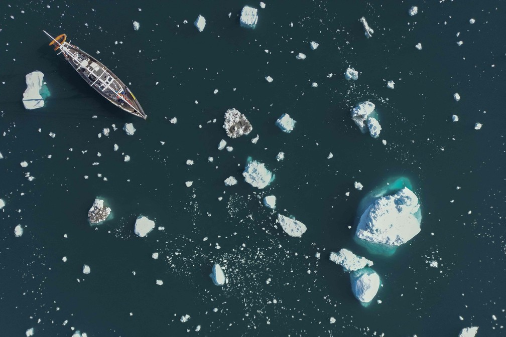 Foto aérea mostra o veleiro 'Kamak' da expedição da Greenlandia, navegando entre icebergs liberados pelas geleiras ao redor de Milne Land devido às altas temperaturas no fiorde de Scoresby Sound, no leste da Groenlândia. — Foto: Olivier MORIN/AFP