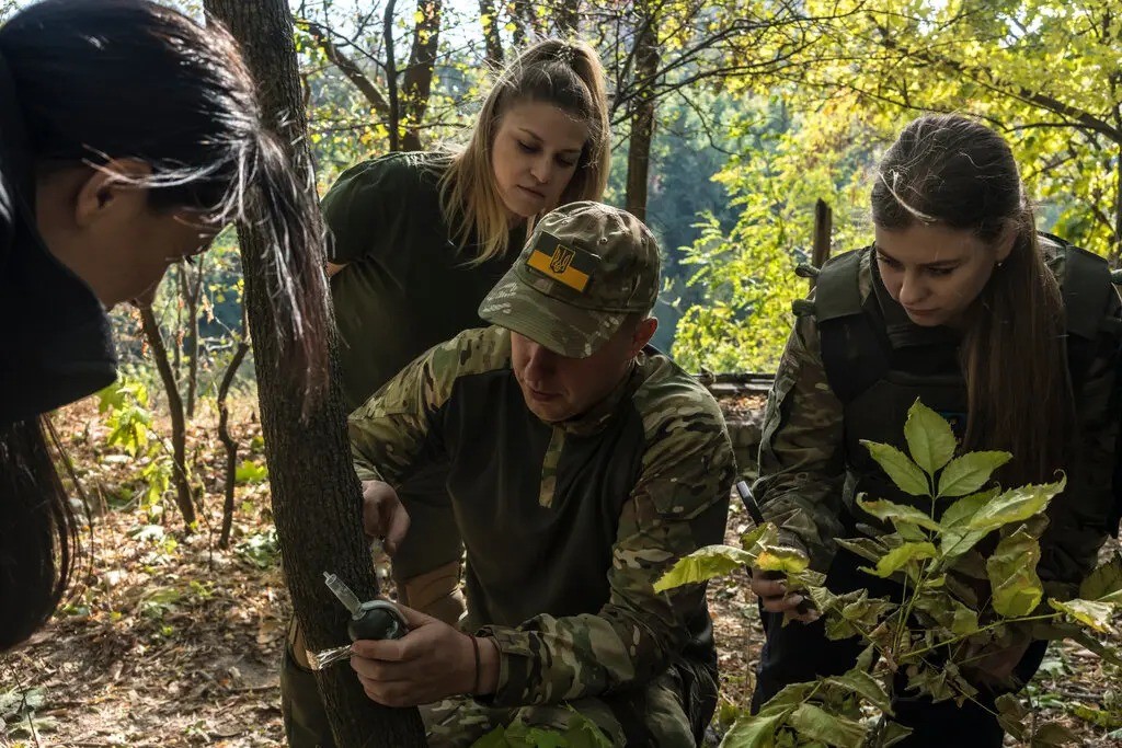 Um dos instrutores do curso demonstrando a criação de uma armadilha com granada e arame — Foto: Brendan Hoffman / New York Times