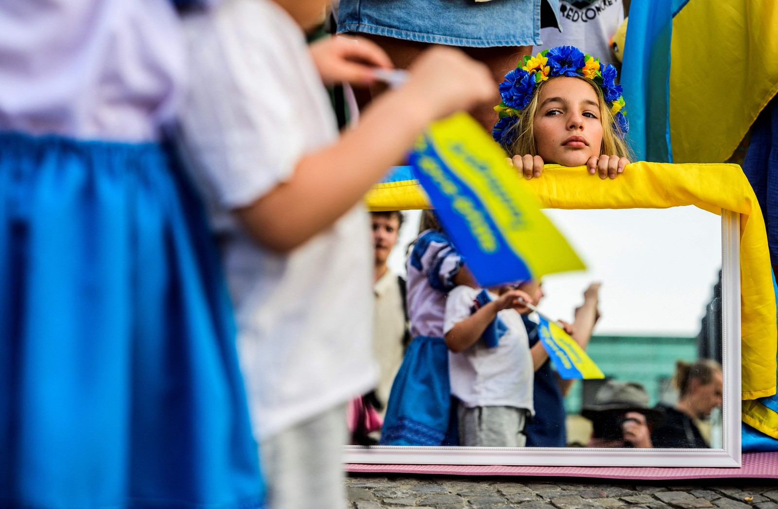 Uma jovem senta-se atrás de um espelho durante um concerto para marcar o Dia da Independência da Ucrânia, em Berlim — Foto: John MACDOUGALL / AFP