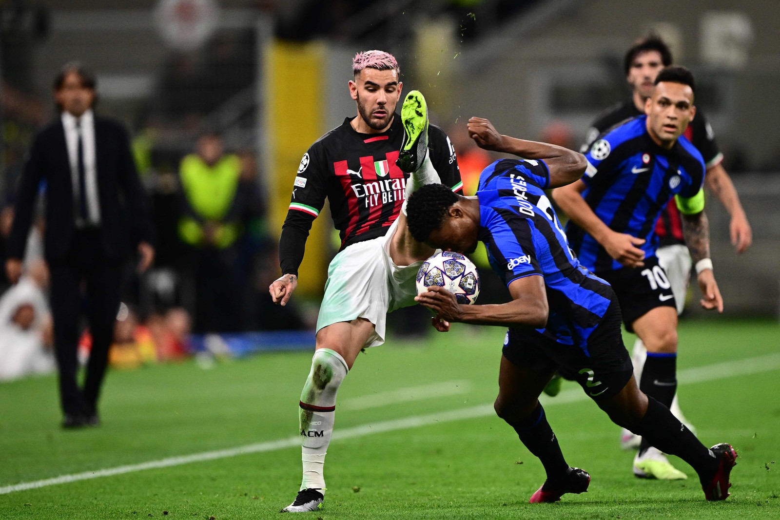 O zagueiro francês do AC Milan Theo Hernandez e o meio-campista holandês do Inter de Milão Denzel Dumfries vão para a bola durante a partida — Foto: BERTORELLO / AFP