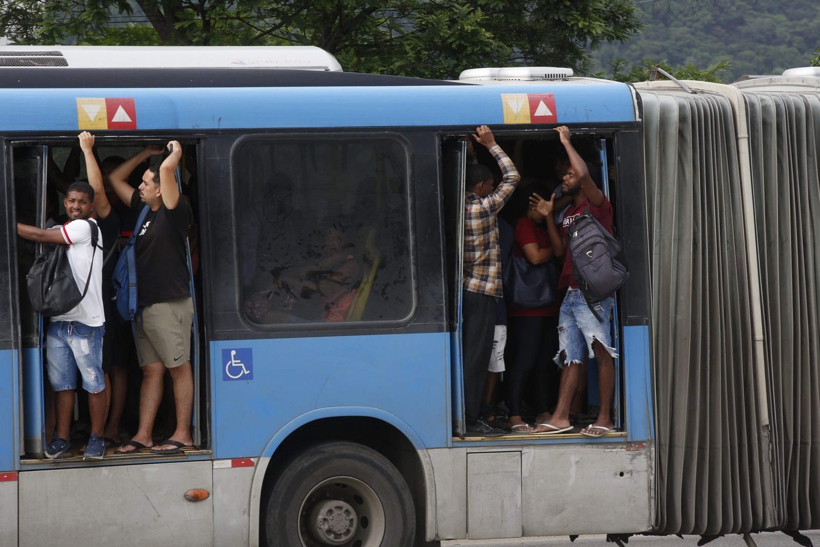 Viajando em perigo: no BRT lotado, as portas vandalizadas põem os passageiros em risco, pois permanecem abertas com os ônibus em movimento — Foto: Custodio Coimbra / Agência O Globo