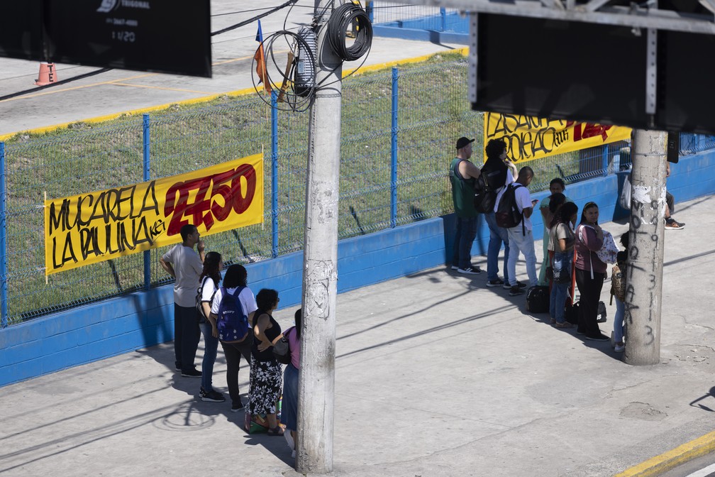 Pessoas se escondem na sombra de postes na Avenida Brasil — Foto: Márcia Foletto/Agência O Globo