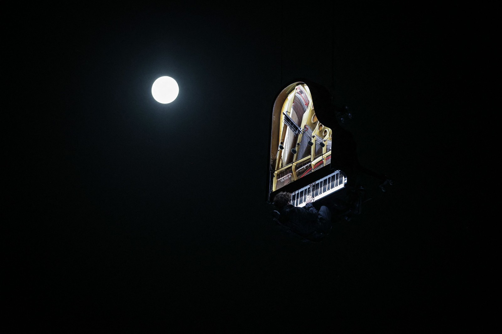 O artista suíço Alain Roche apresenta uma performance em meio à última Superlua do ano em Bourdeaux, na França — Foto: Thibaud MORITZ / AFP