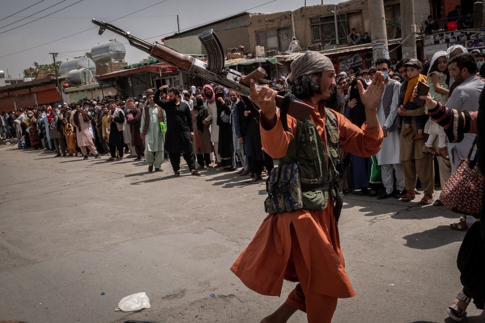 Militante talibã ameaça pessoas que aguardam do lado de fora do aeroporto de Cabul, em agosto de 2021 — Foto: Jim Huylebroek/The New York Times