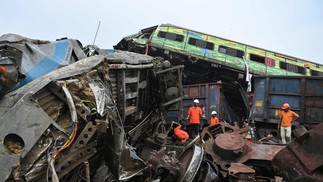 Equipes de resgate se reúnem em torno dos trens danificados no local da colisão perto de Balasore, a cerca de 200 km da capital do estado Bhubaneswar — Foto: Dibyangshu SARKAR / AFP)