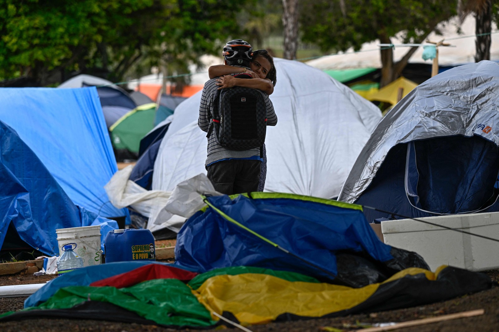 Apoiadores do ex-presidente de extrema-direita Jair Bolsonaro se abraçam enquanto soldados desmantelam o acampamento. — Foto: Mauro Pimentel / AFP