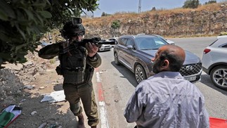 Soldado israelense interrompe o avanço de uma procissão fúnebre, de um homem palestino morto durante confrontos com as forças israelenses, em um posto de controle que sai da aldeia palestina de Nilin, a oeste de Ramallah, na Cisjordânia ocupada  — Foto: ABBAS MOMANI / AFP