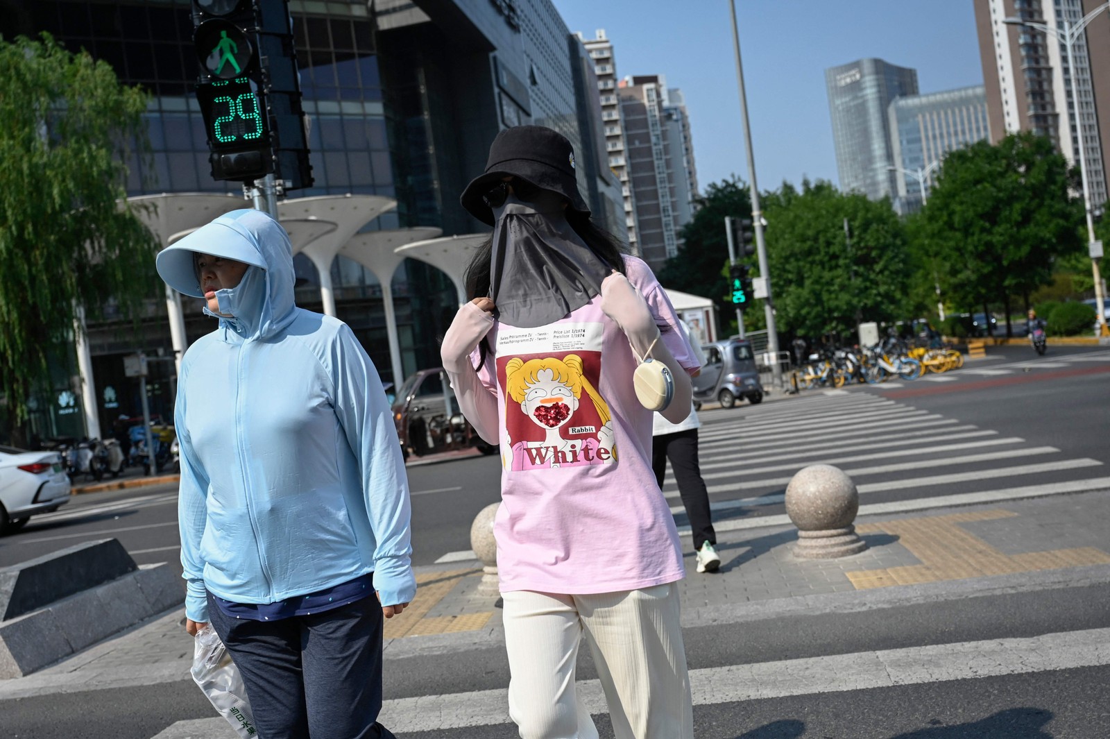 Pessoas se cobrem para se proteger do sol durante as ondas de calor em Pequim.  — Foto: Jade Gao / AFP