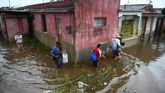 Pessoas caminham por uma rua inundada em Batabano, província de Mayabeque, Cuba — Foto: Yamil LAGE/AFP