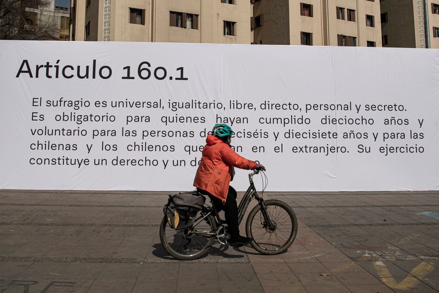 Ciclista passa em frente a mural com artigo do projeto de Constituição em Santiago