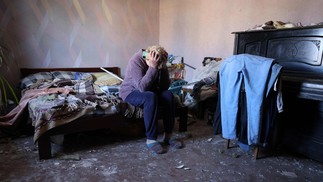 A moradora local Oksana, 54 anos, reage ao quarto de sua casa, que foi danificado por um ataque de mísseis na vila de Krasylivka, região de Kiev — Foto: Anatolii STEPANOV/AFP