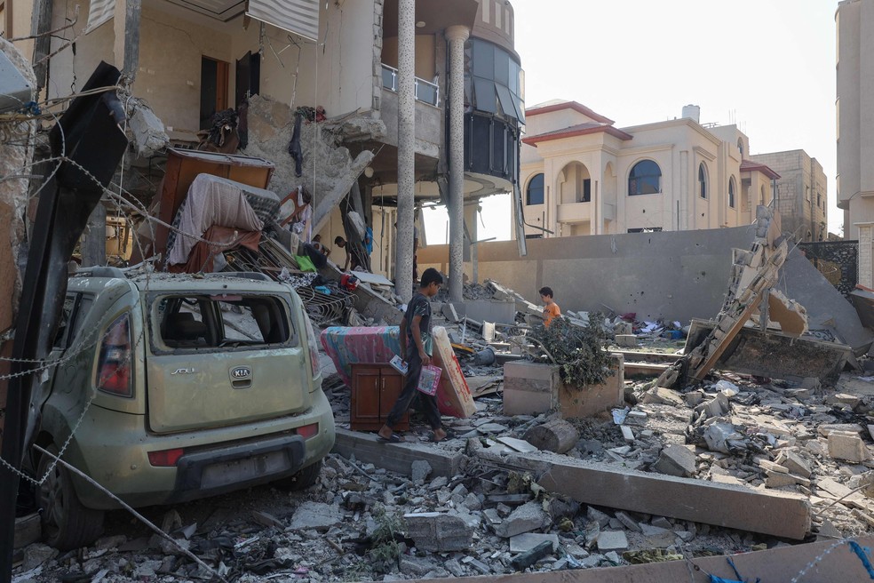 Palestinos vasculham escombros de casa no campo de refugiados de Nuseirat — Foto: Eyad Baba/AFP