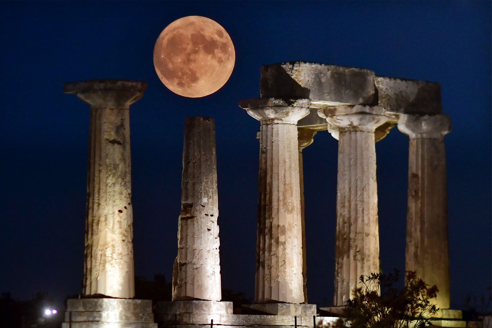 A "Superlua Azul", a segunda lua cheia de um mês de agosto, surge acima do Templo de Apolo, na antiga Corinto, Grécia. — Foto: Valerie GACHE / AFP