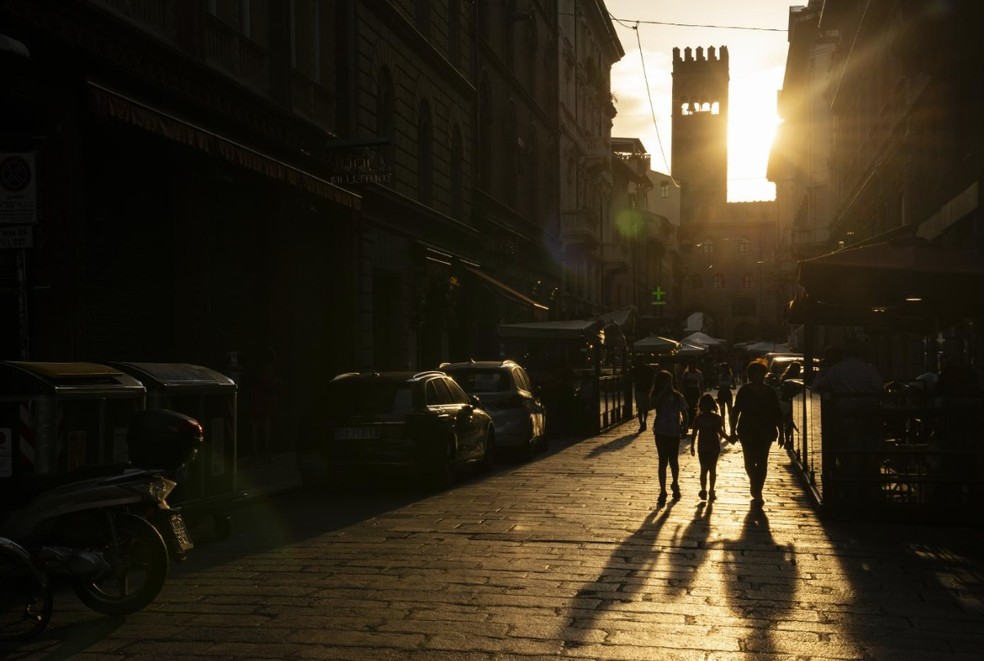 Pessoas andam no meio de uma rua de Bolonha, próxima à Piazza Maggiore e à torre do Palazzo del Podesta — Foto: Susan Wright/The New York Times