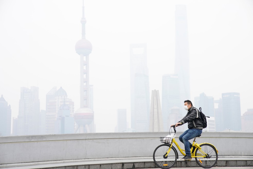 Em Xangai, ciclista pedala com o distrito financeiro de Pudong ao fundo encoberto pela poluição: livro ajuda a entender os caminhos tomados pela China Reuters — Foto:         
