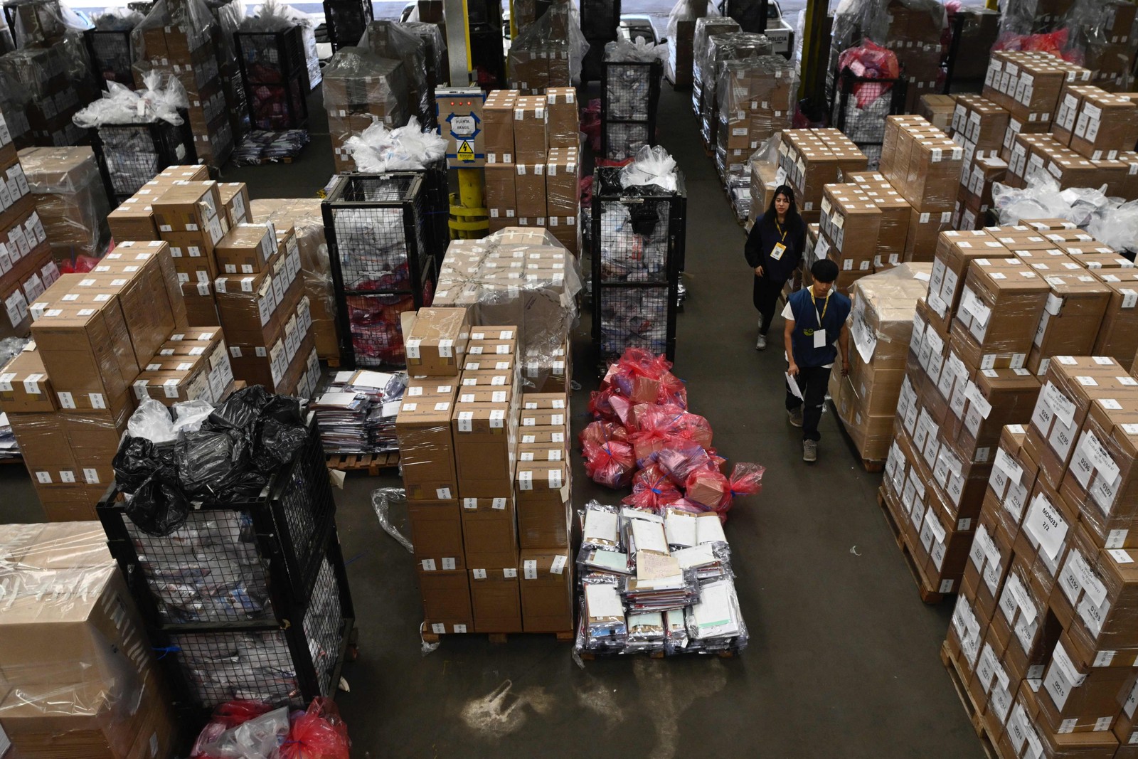 Trabalhadores caminham em meio a urnas dentro de um depósito dos Correios da Argentina, antes das próximas eleições presidenciais de 22 de outubro. — Foto: Luis ROBAYO / AFP