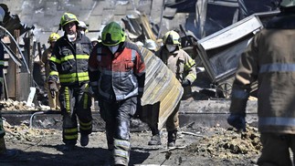 Trabalhadores fazem a limpeza dos escombros do shopping Amstor, um dia depois de ter sido atingido por um ataque de míssil russo, em Kremenchuk, na Ucrânia — Foto: GENYA SAVILOV / AFP