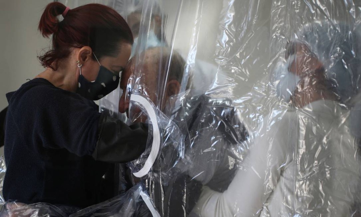 Suzana Lisboa abraça seu pai, Raul Lisboa, 89 anos, através de uma cortina de plástico instalada em abrigo para idosos em São Paulo — Foto: RAHEL PATRASSO / REUTERS