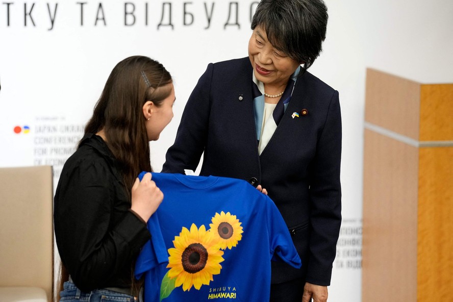 Chanceler japonesa, Yoko Kamikawa (D), entrega presente a refugiada ucraniana durante conferência sobre a reconstrução da Ucrânia, em Tóquio