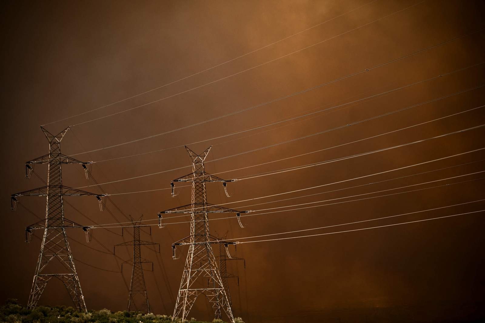 Torres de transmissão são atingidos pelo incêndio florestal em Chasia, nos arredores de Atenas — Foto: Angelos Tzortzinis / AFP