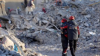 Agentes de resgate se consolam com os escombros de edifícios desabados em Nurdagi, perto de Gaziantep, Turquia — Foto: ZEIN AL RIFAI/AFP