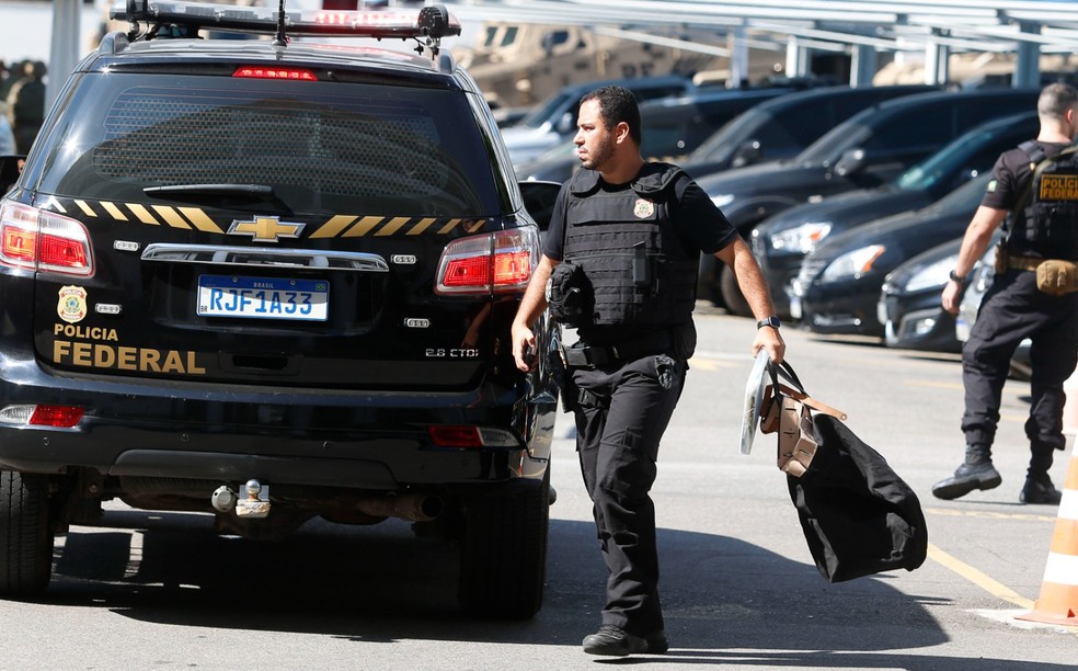 Um agente da PF carrega material apreendido durante a Operação Dinastia II — Foto: Fabiano Rocha/Agência O Globo