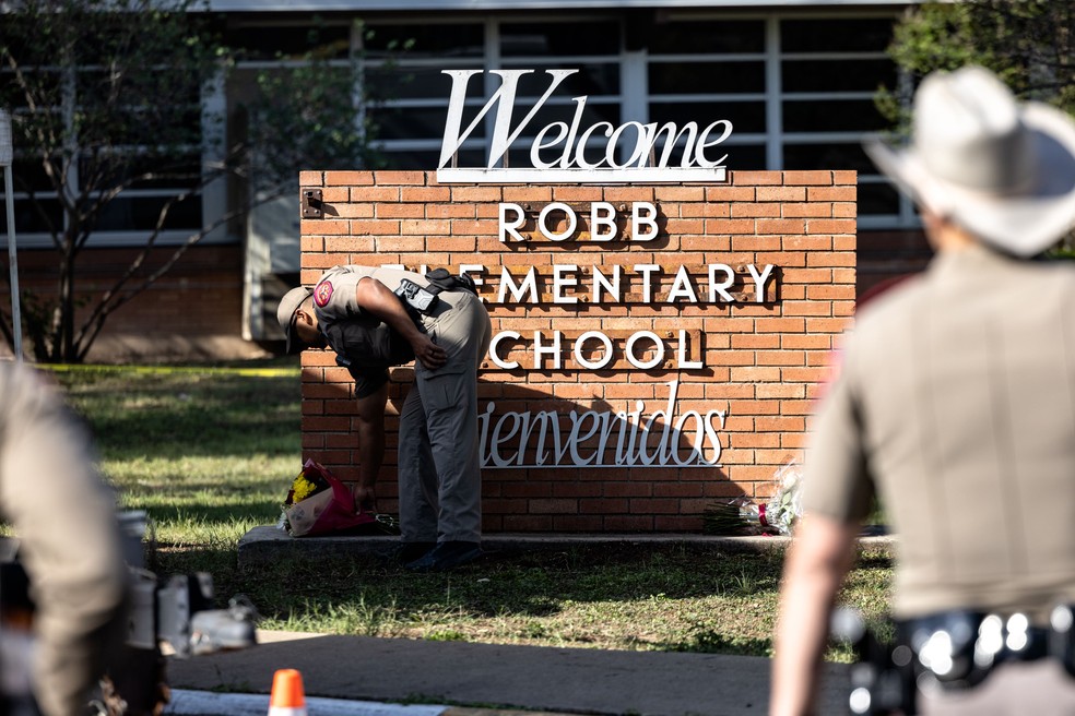 Policial coloca flores para vítimas do massacre na Robb  Elementary School, no Texas — Foto: Jordan Vonderhaar/Getty Images/AFP