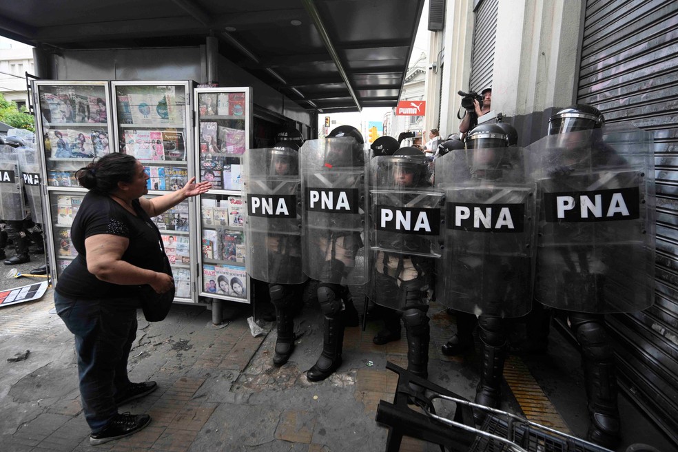 Uma mulher fala com as forças de segurança que montam guarda enquanto membros de movimentos sociais protestam contra cortes do governo do presidente Javier Milei nos setores mais vulneráveis. — Foto: Luis ROBAYO / AFP