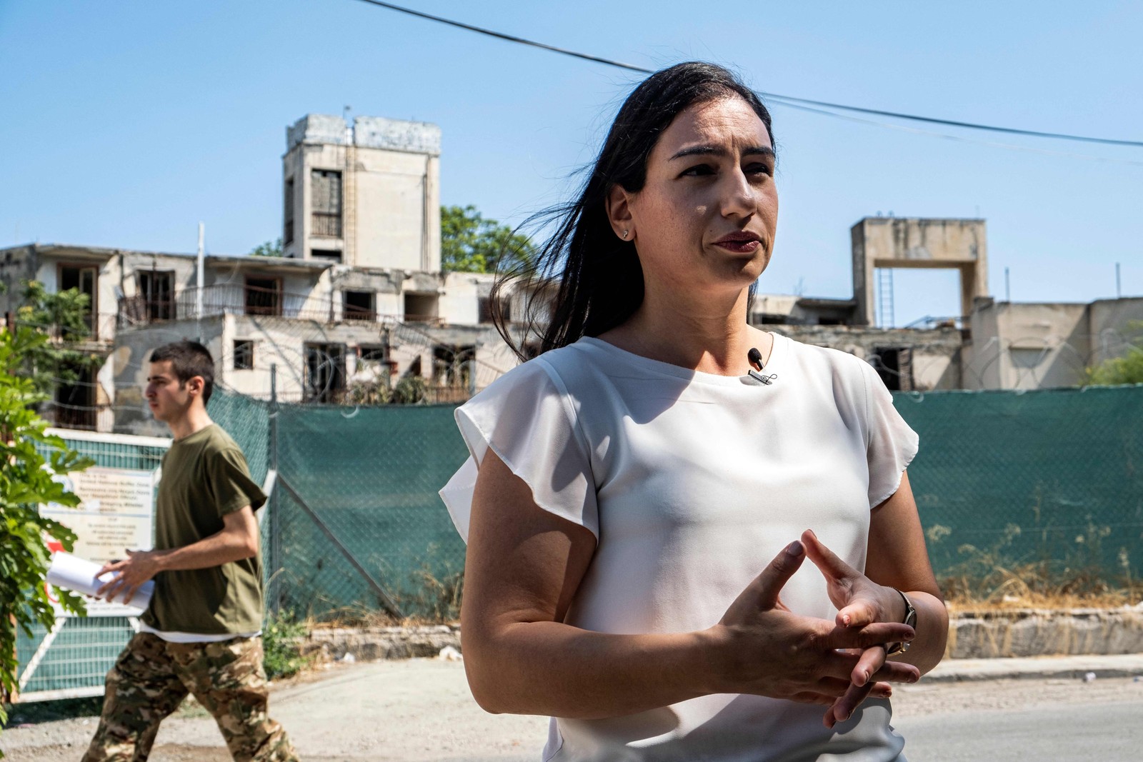 A especialista em 'turismo sombrio' Katerina Antoniou em frente ao portão que impede o acesso à Linha Verde em Nicósia, a zona militarizada que divide o Chipre em dois desde 1974 — Foto: Amir Makar / AFP