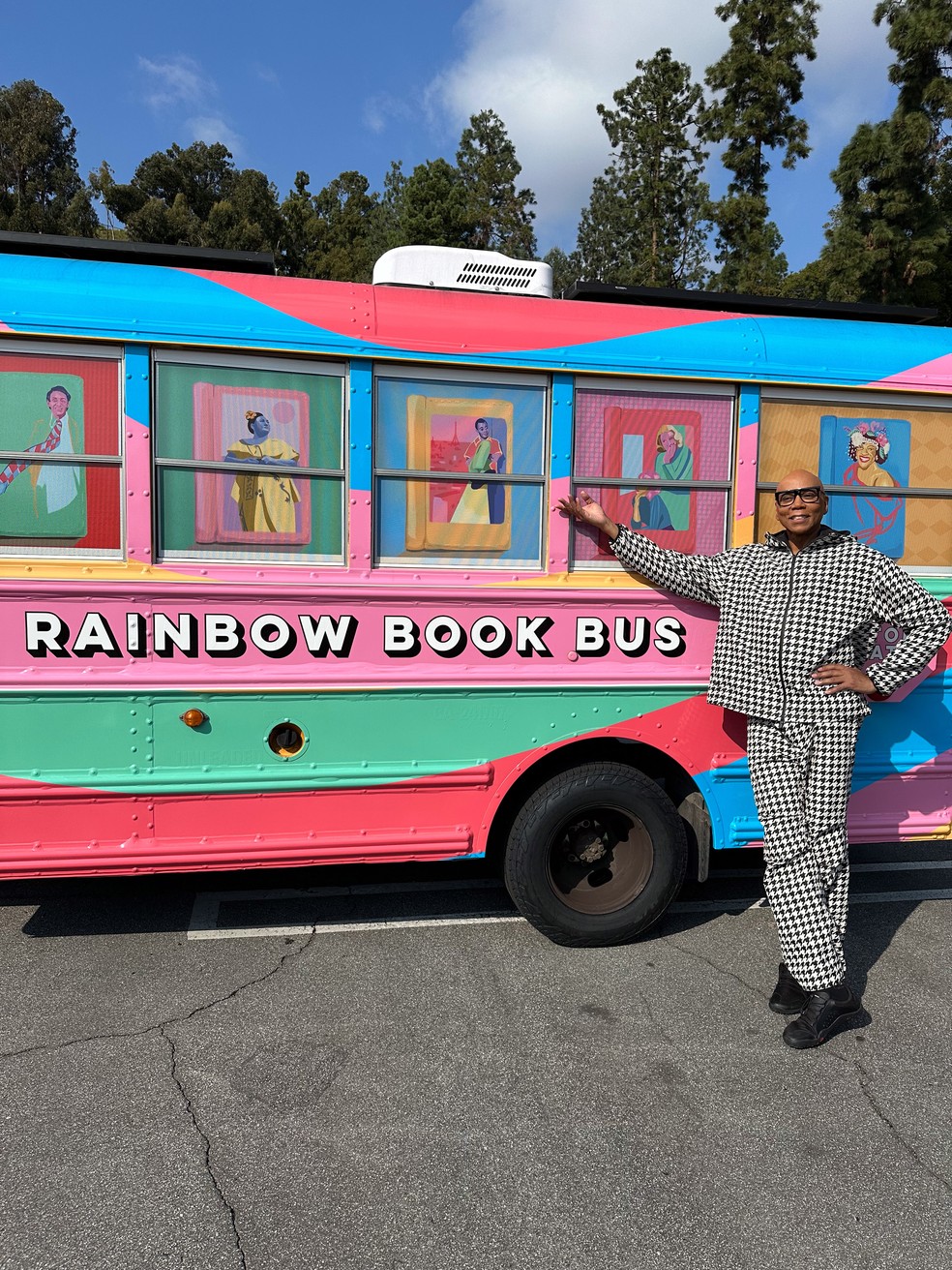 RuPaul ao lado do ônibus escolar nas cores do arco-íris que vai viajar pela Costa Oeste e Sul dos EUA para distribuir livros que foram alvo de censura — Foto: Divulgação / NYT