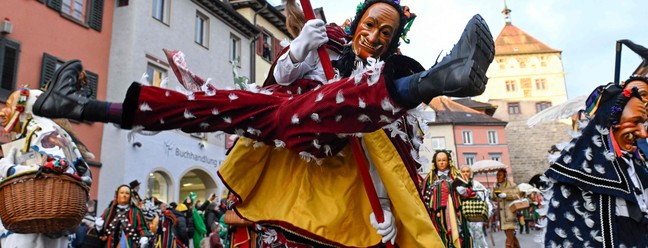 Folião, vestido como o personagem tradicional Federhannes, brinca o carnaval nas ruas de Rottweil, cidade no sul da Alemanha — Foto: Thomas Kienzle / AFP
