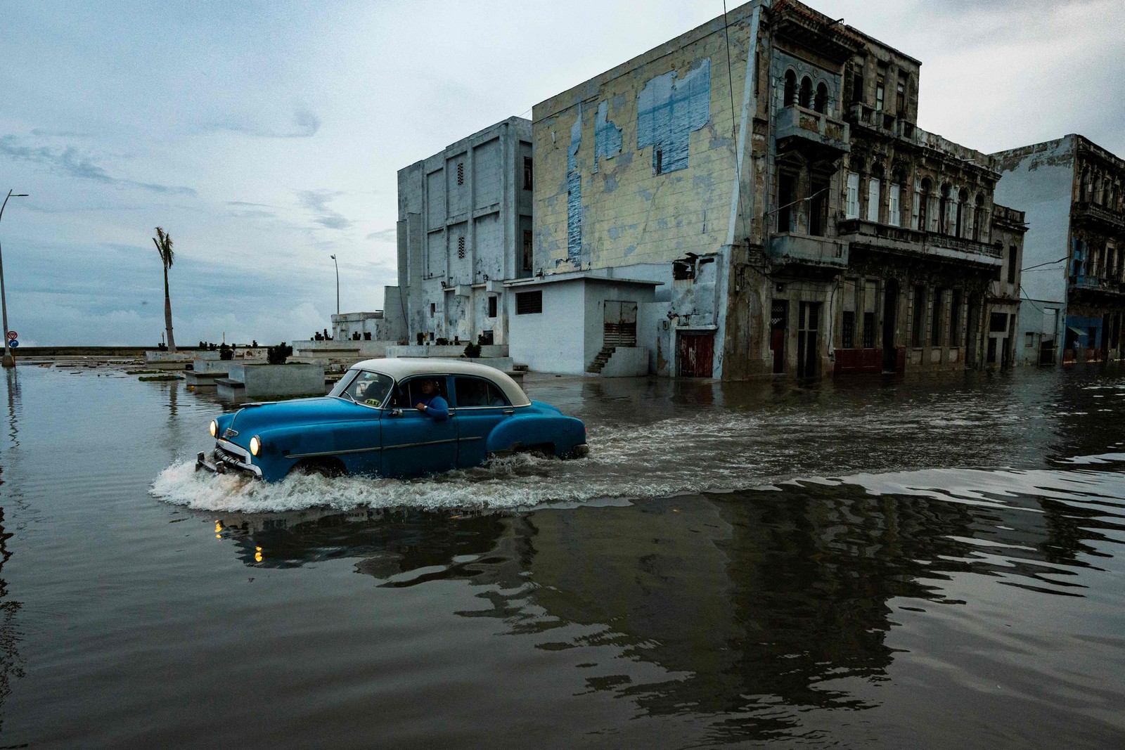 Carro passa por uma rua inundada em Havana — Foto: YAMIL LAGE / AFP