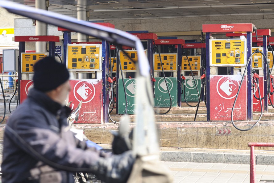 Homem espera em posto de gasolina do Teerã, capital do Irã, durante ataque cibernético que paralisou vendas de combustível