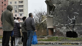 Moradores observam obra 'estilo Banksy' na cidade de Irpin em 12/11/22 — Foto: Genya SAVILOV / AFP