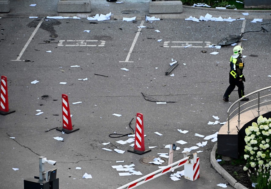 Bombeiro caminha entre papéis e vidros quebrados, do lado de fora de um bloco de escritórios danificado do Moscow International Business Center, após um ataque de drone ucraniano