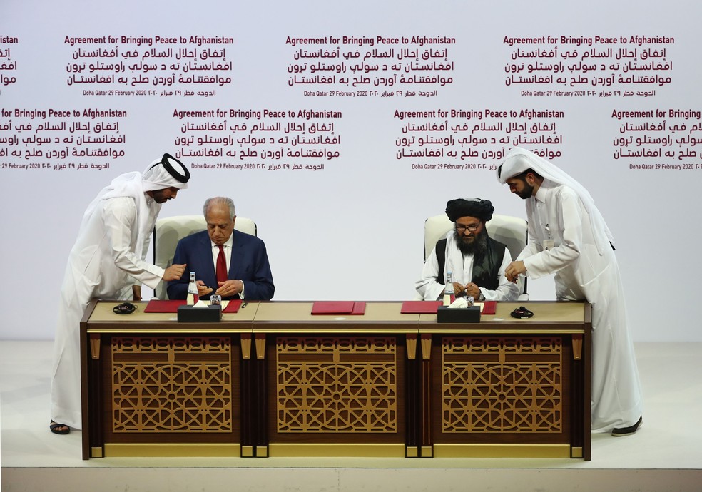 Representantes dos EUA, Zalmay Khalilzad (E), e do Talibã, Abdul Ghani Baradar, assinam acordo em Doha, em fevereiro de 2020 — Foto: KARIM JAAFAR / AFP