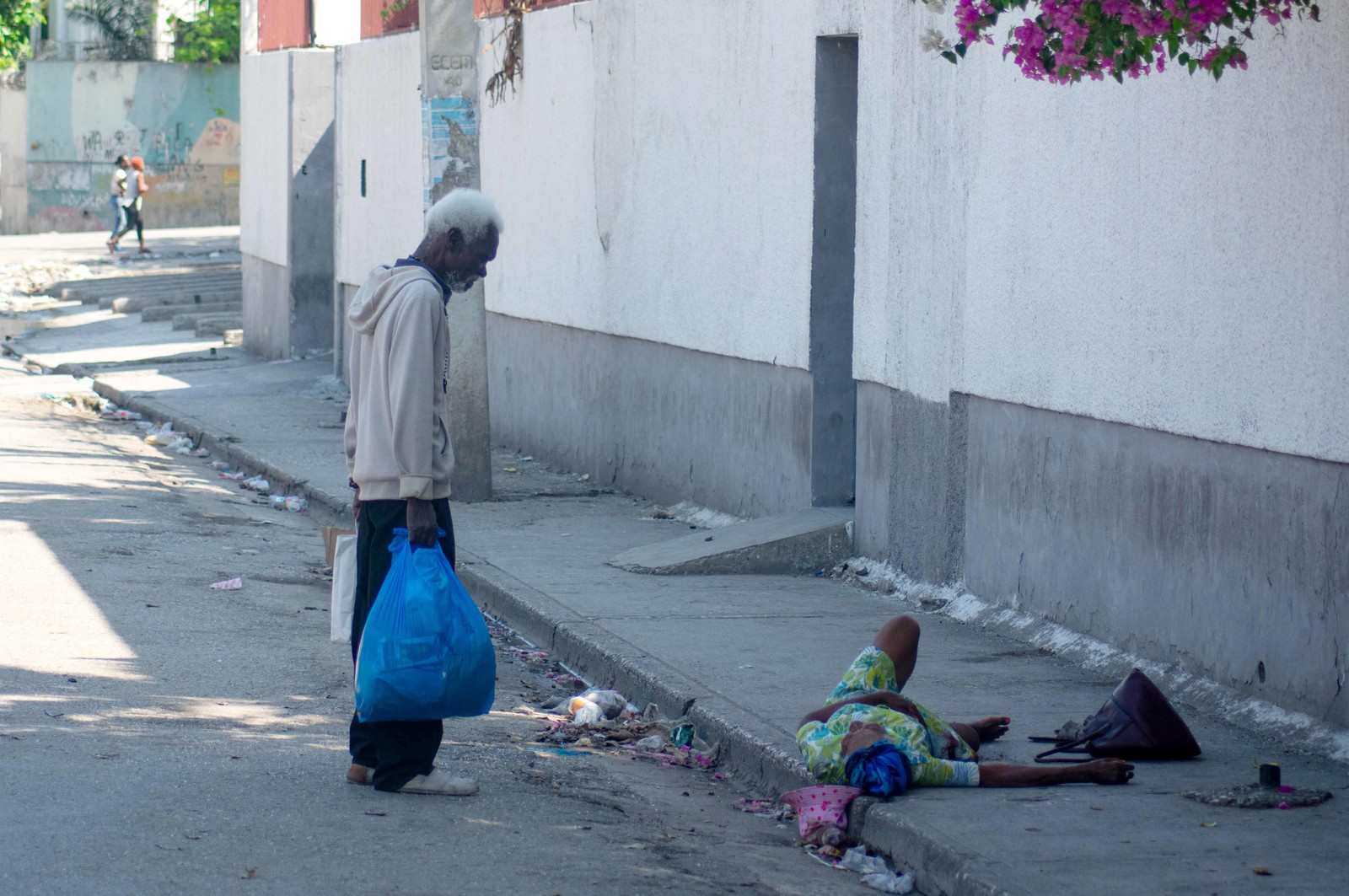 Um homem se esforça para ajudar uma mulher idosa que foi baleada no pé, em Porto Príncipe, Haiti. — Foto: Clarens SIFFROY / AFP