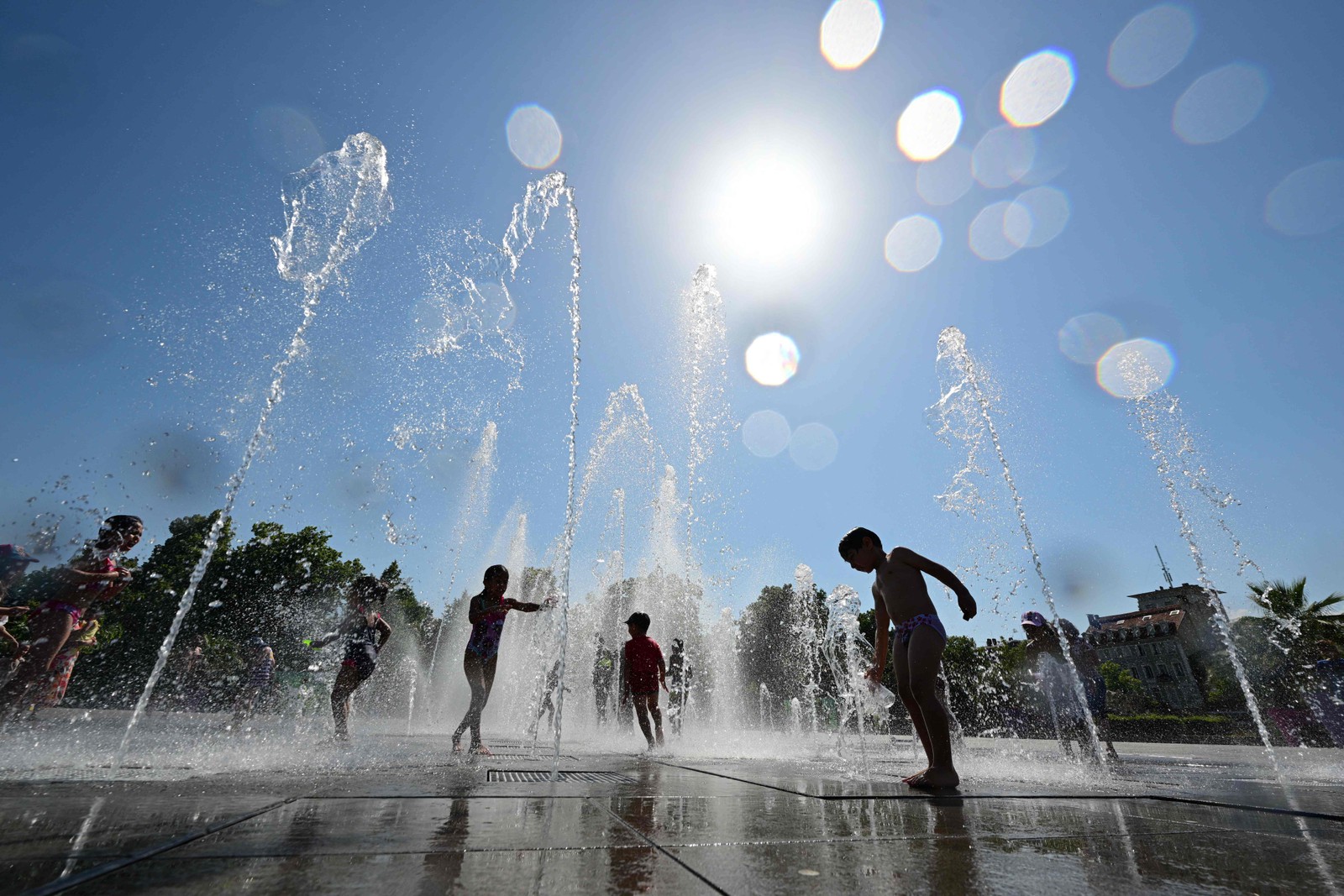 Crianças se refrescam em uma fonte em Colmar, leste da França, enquanto país enfrenta onda de calor, cruzando a marca de 40°C . — Foto: SEBASTIEN BOZON / AFP