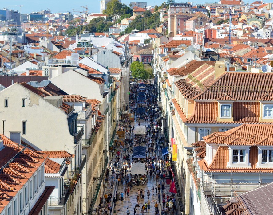 Pedestres caminham em uma rua de Lisboa