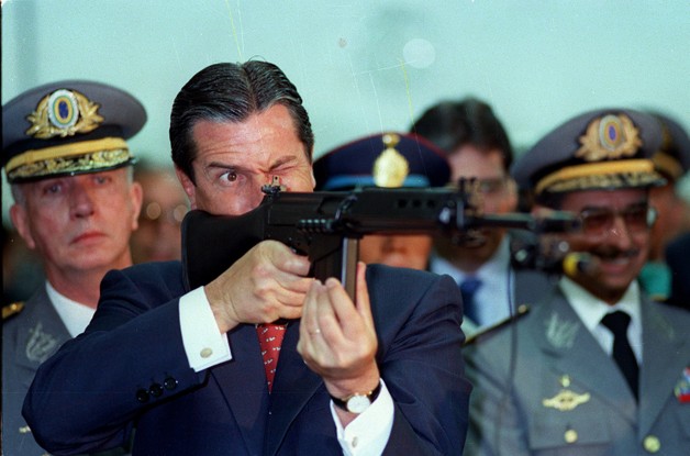 O presidente Fernando Collor durante cerimônia militar aponta um fuzil do Exército, em 1990