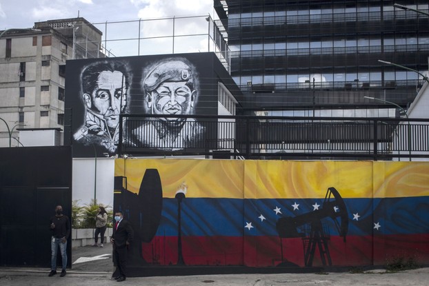 Imagens do falecido presidente Hugo Chávez e Simon Bolívar acima de um mural dos macacos da bomba de petróleo em Caracas, Venezuela