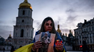 Mulher ucraniana segura uma vela e um retrato de seu marido que foi capturado durante o cerco à cidade portuária de Mariupol — Foto: DIMITAR DILKOFF/AFP